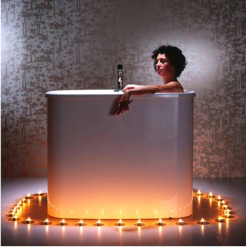 AQVA Haiku Solo 1300 with a person seated deeply immersed, candle ring in frame
